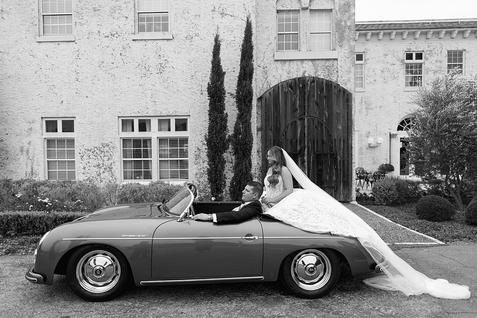 bride and groom in a vintage porsche outside of Bella Cosa wedding venue in lake wales florida